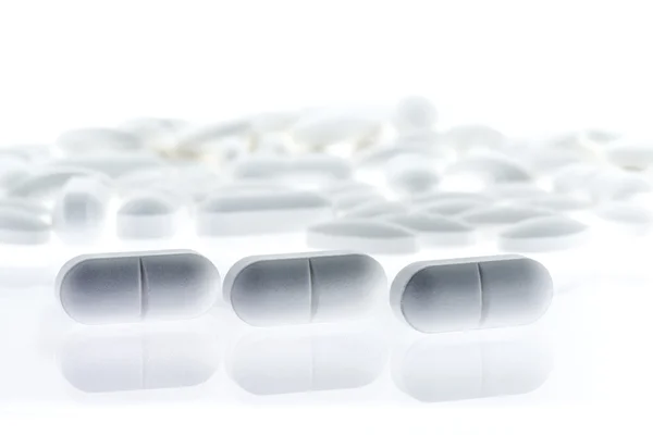 Drie witte pillen met reflectie — Stockfoto