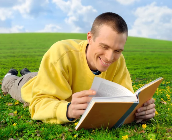 Man on a meadow reading cheerfully — Stock Photo, Image