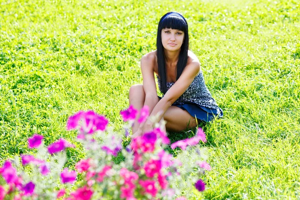 Jonge brunette zittend op het gras — Stockfoto