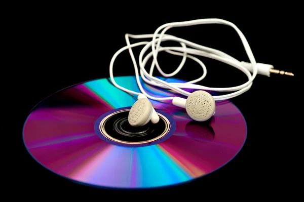Earphones lying on a compact disc — Stock Photo, Image