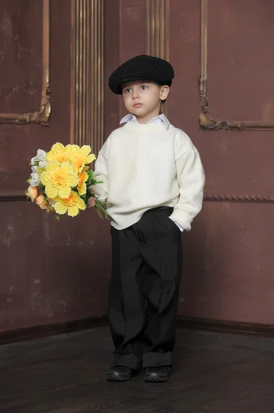 Little boy wearing a cap with flowers in their hands — Stock Photo, Image