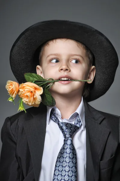 Kleiner Junge mit einer Mütze mit Blumen in den Händen — Stockfoto