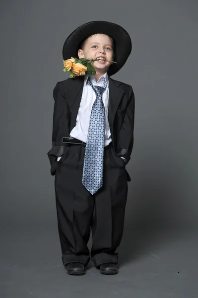 Menino usando um boné com flores nas mãos — Fotografia de Stock