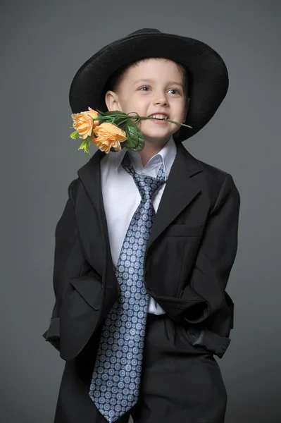 Маленький мальчик в шапке с цветами в руках — стоковое фото