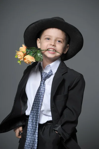 Little boy wearing a cap with flowers in their hands — Stock Photo, Image