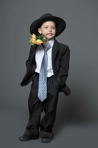 Malý kluk na sobě čepici s květinami v rukou — Stock fotografie