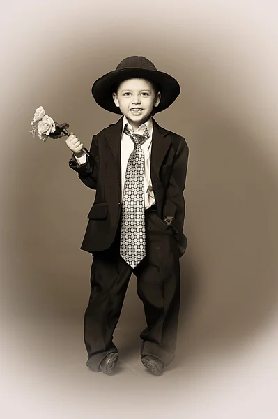 Kleiner Junge mit einer Mütze mit Blumen in den Händen — Stockfoto
