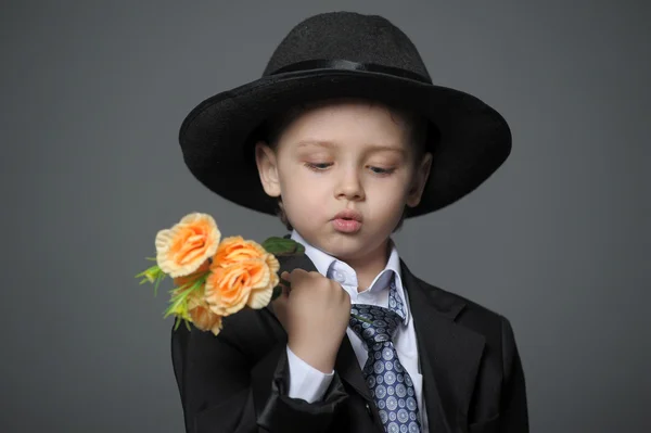 Mały chłopiec czapce z kwiatami w swoje ręce — Zdjęcie stockowe
