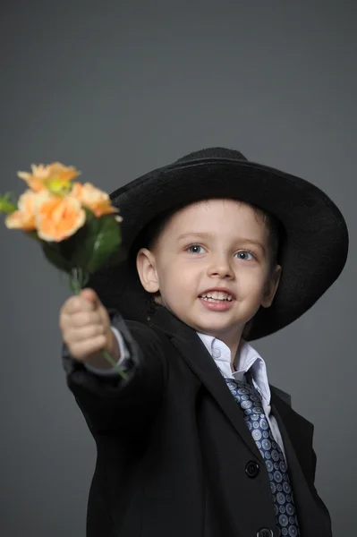Malý kluk na sobě čepici s květinami v rukou — Stock fotografie