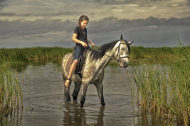 teen girl on a horse in water clipart