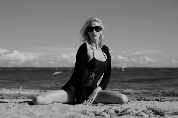 Sexig blondin i svart på stranden — Stockfoto