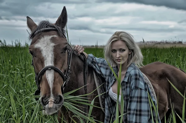 Sexy blonde naast het paard — Stockfoto