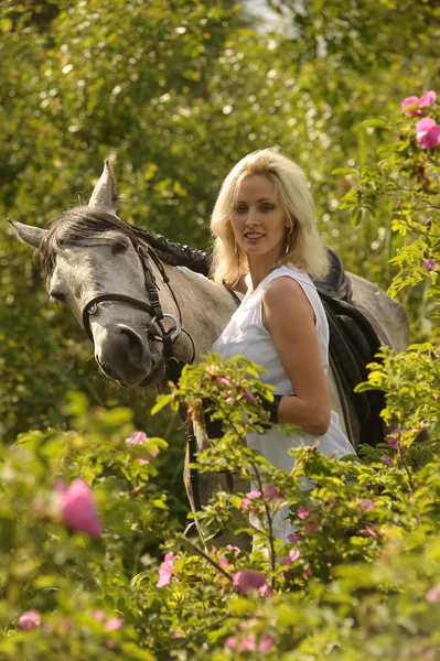 Blond meisje met een paard — Stockfoto