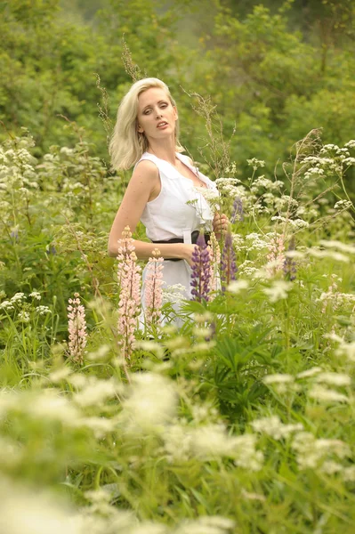 Dziewczyna w białej sukni, w polu wśród kwiatów — Zdjęcie stockowe