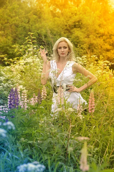 Девушка в белом платье в поле среди цветов — стоковое фото