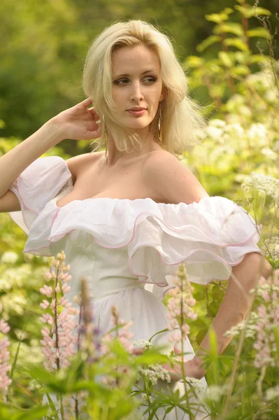 Chica en un vestido blanco en el campo entre las flores — Foto de Stock
