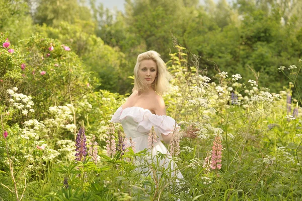 Flicka i en vit klänning i fältet bland blommorna — Stockfoto