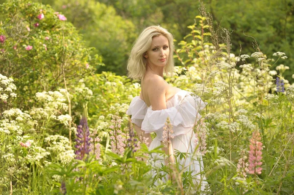 Çiçekler arasında alanındaki beyaz elbiseli kız — Stok fotoğraf
