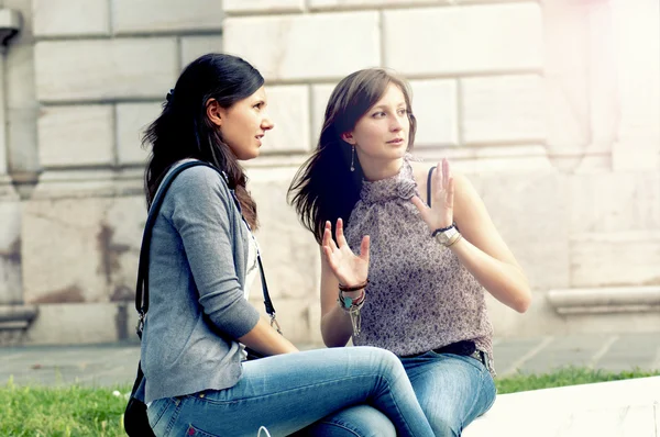 Två flickor medan du talar ser i mobilen — Stockfoto
