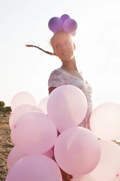 Mädchen von Luftballons umgeben von den Sonnenstrahlen — Stockfoto