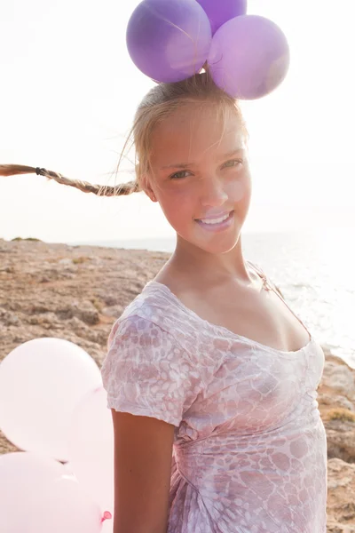 Menina cercada por balões pelos raios de luz solar — Fotografia de Stock