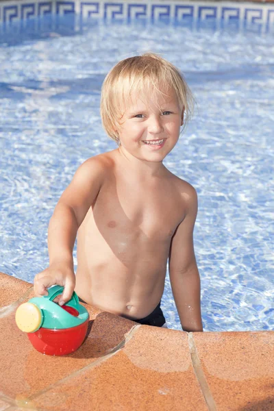 Menino com regador na piscina — Fotografia de Stock