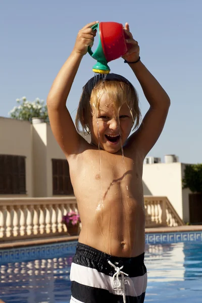 Chłopiec z podlewanie może w basenie — Zdjęcie stockowe