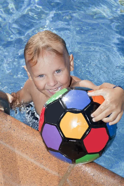 Chłopiec z piłką kolor jest w basenie — Zdjęcie stockowe