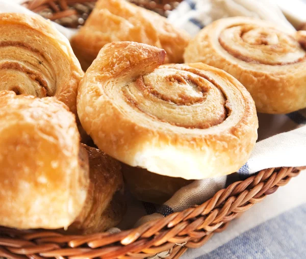 Cinnamon danish bun in the basket on textile background — Stockfoto