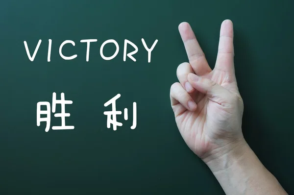 Victory gesture on a blackboard background — Stock Photo, Image