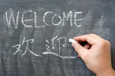 Welcome - word written on a blackboard with a Chinese version clipart