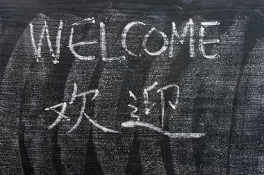 Welcome - word written on a blackboard with a Chinese version clipart