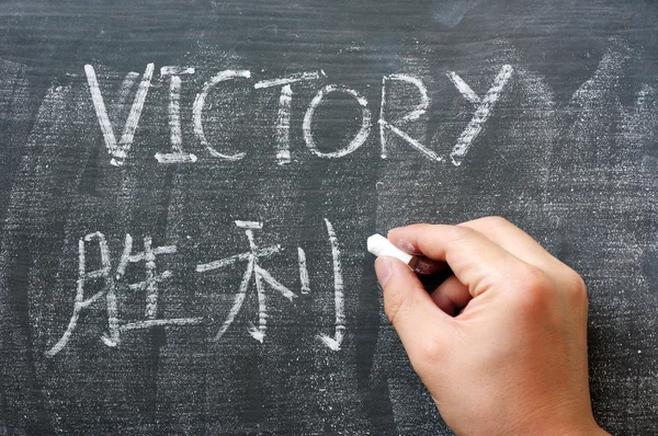 Victory - word written on a blackboard with a Chinese translation — Stock Photo, Image