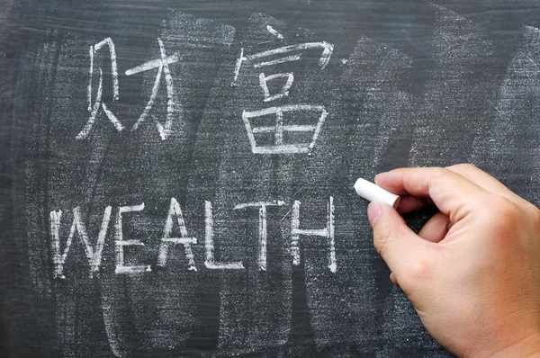 Багатства - слово, написане на дошці з китайською мовою — стокове фото