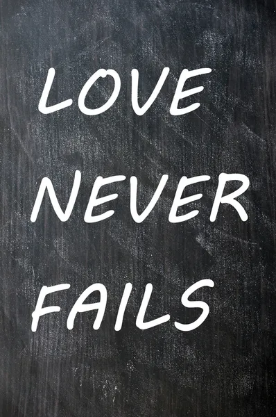 Miłość nigdy nie zawodzi napisał na tablicy rozmazany — Zdjęcie stockowe