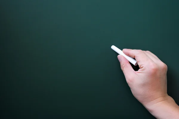 Blackboard bakgrund med en hand som håller krita skriva. — Stockfoto