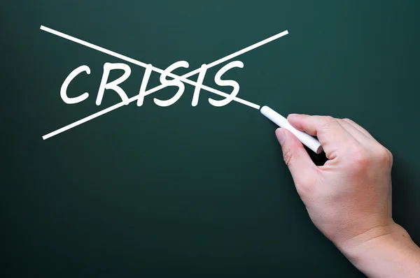 Crossing out crisis on a green chalkboard — Stock Photo, Image