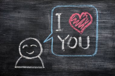 Speech bubble with a cartoon figure, saying I love you drawn on a blackboard background clipart