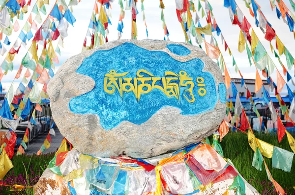 Тибетские молитвенные флаги и маникюрный камень — стоковое фото
