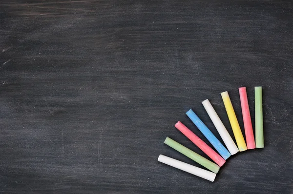 Kleurrijke krijt op een lege vlekkerig schoolbord — Stockfoto