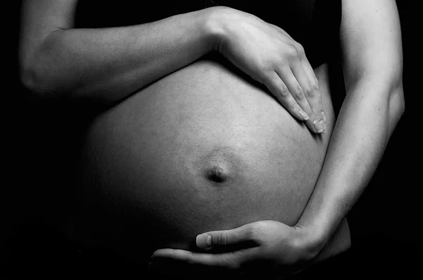 Buik van zwangere vrouw over donkere achtergrond — Stockfoto