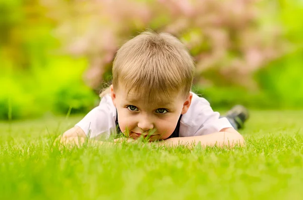 เด็กชายนอนบนหญ้าสีเขียว — ภาพถ่ายสต็อก