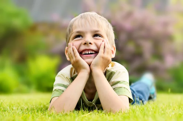 Küçük çocuk bir yeşil çim üzerinde yalan — Stok fotoğraf