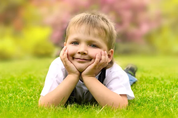 Kleiner Junge liegt auf einem grünen Gras — Stockfoto