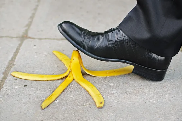 Podnikatel chystá uklouznutí a pádu na oloupaný banán — Stock fotografie