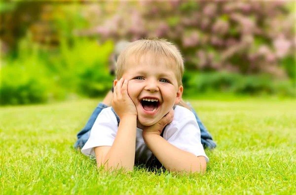 Malý chlapec leží na zelené trávě — Stock fotografie