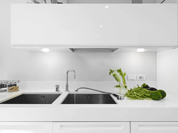 Verduras cerca del grifo en la moderna cocina blanca —  Fotos de Stock