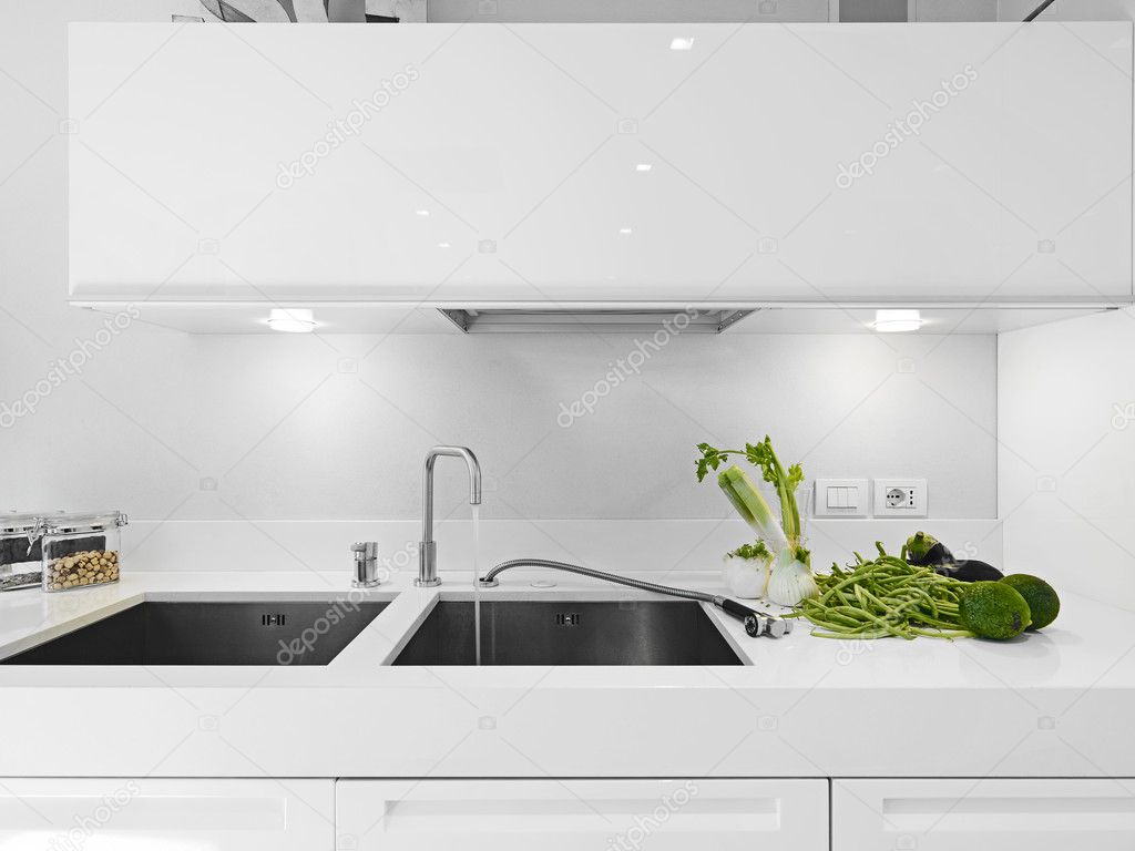 Vegetables near the faucet in the modern white kitchen
