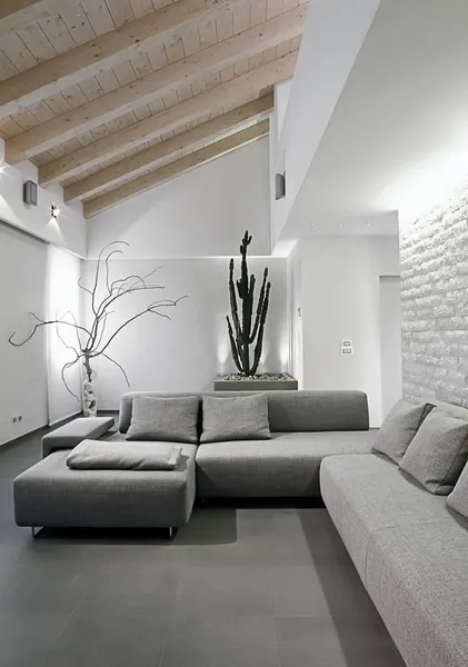 Modern grå soffa i vindsrum Stockfoto