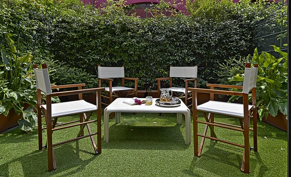 Liten trädgård med fåtöljer och bord — Stockfoto